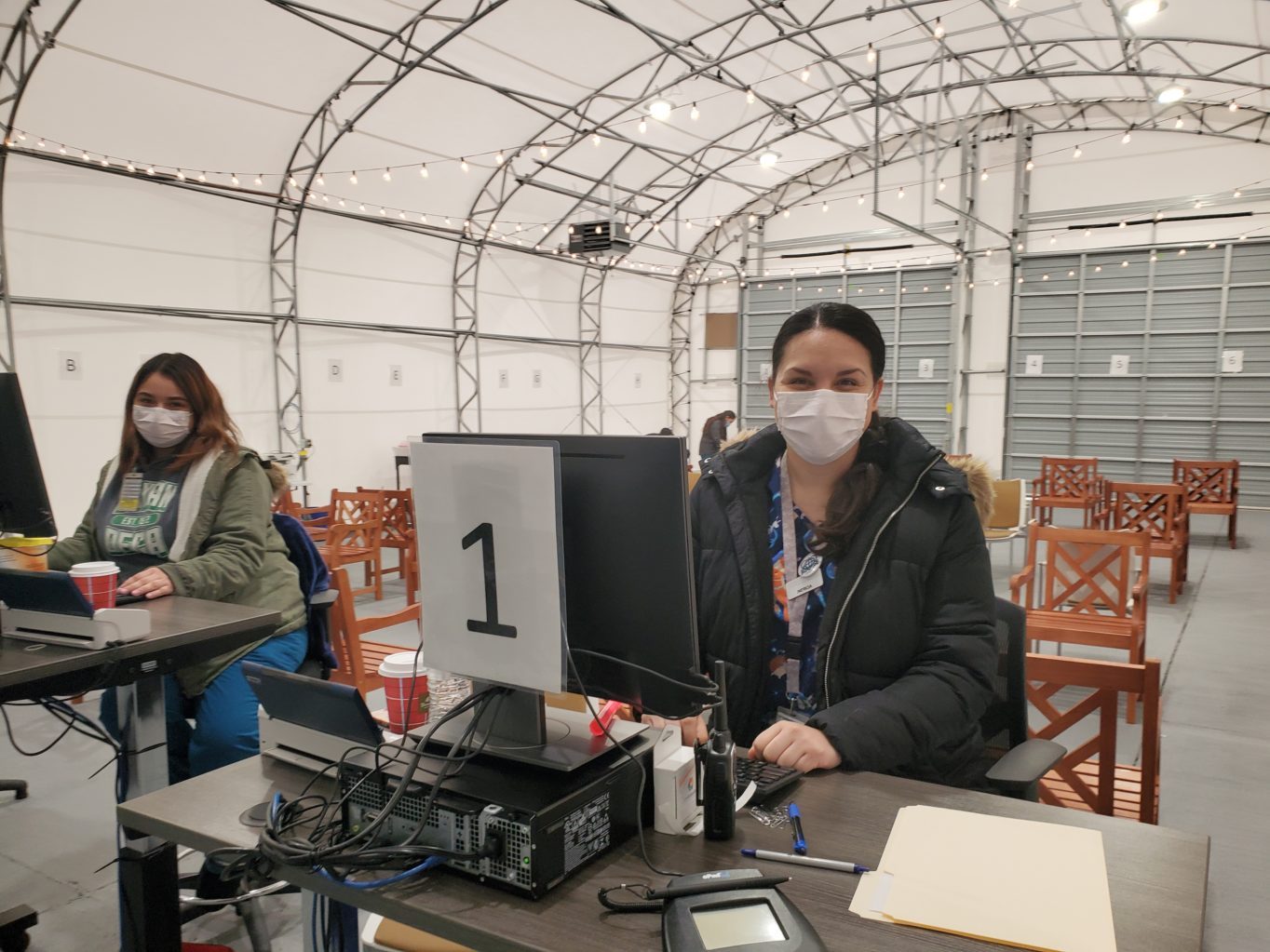 A person wearing a face mask sitting at a desk with a computer