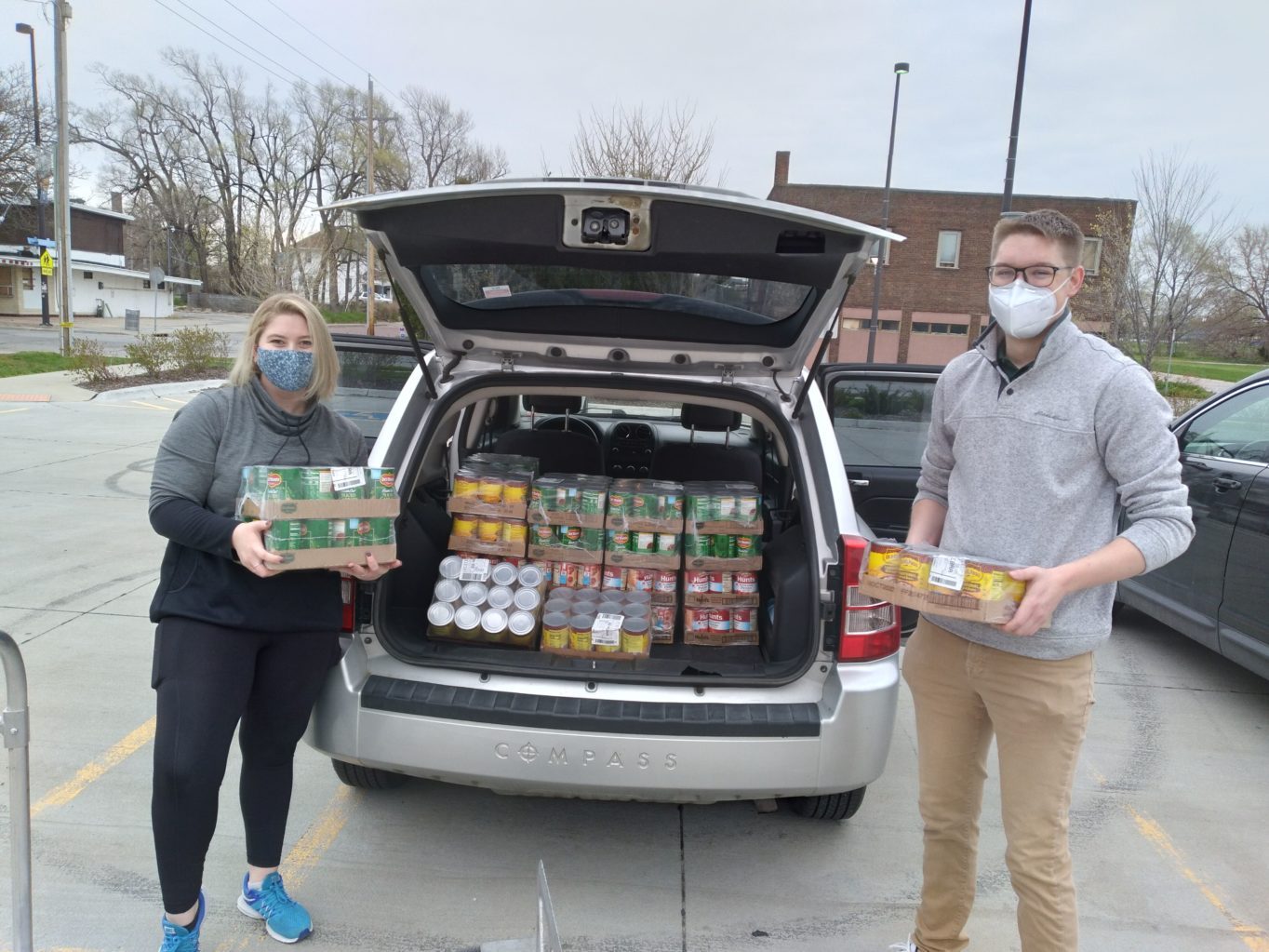 A person and person holding boxes of food in the back of a car