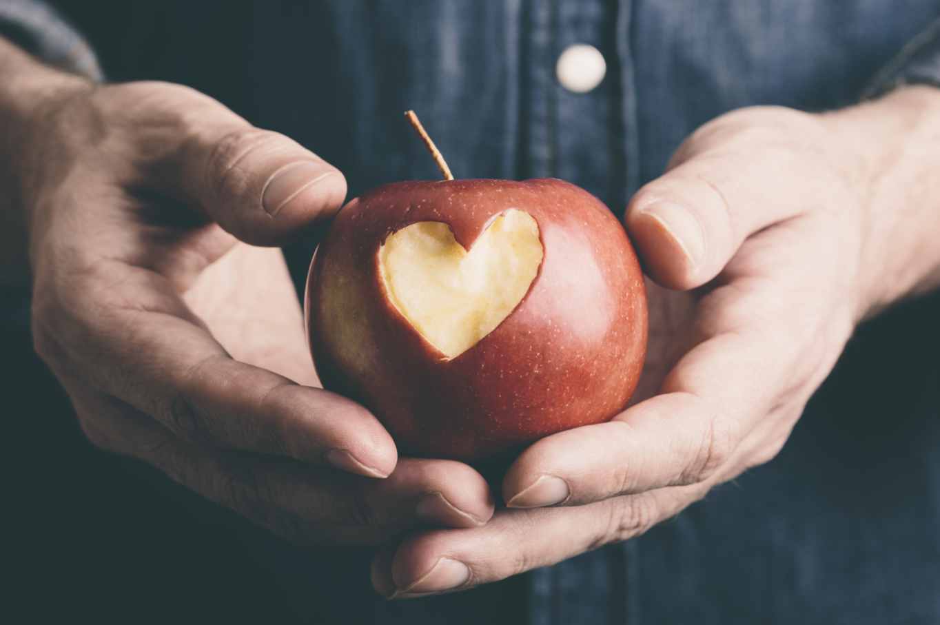 A person holding an apple with a heart cut out