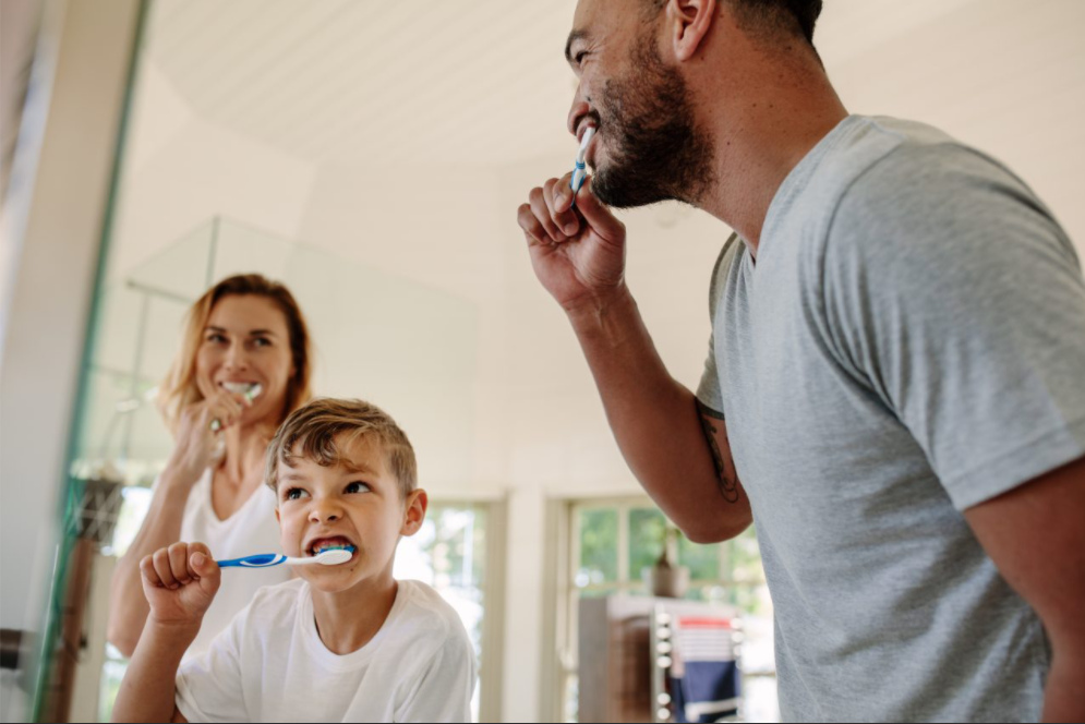 A couple and their child brushing their teeth