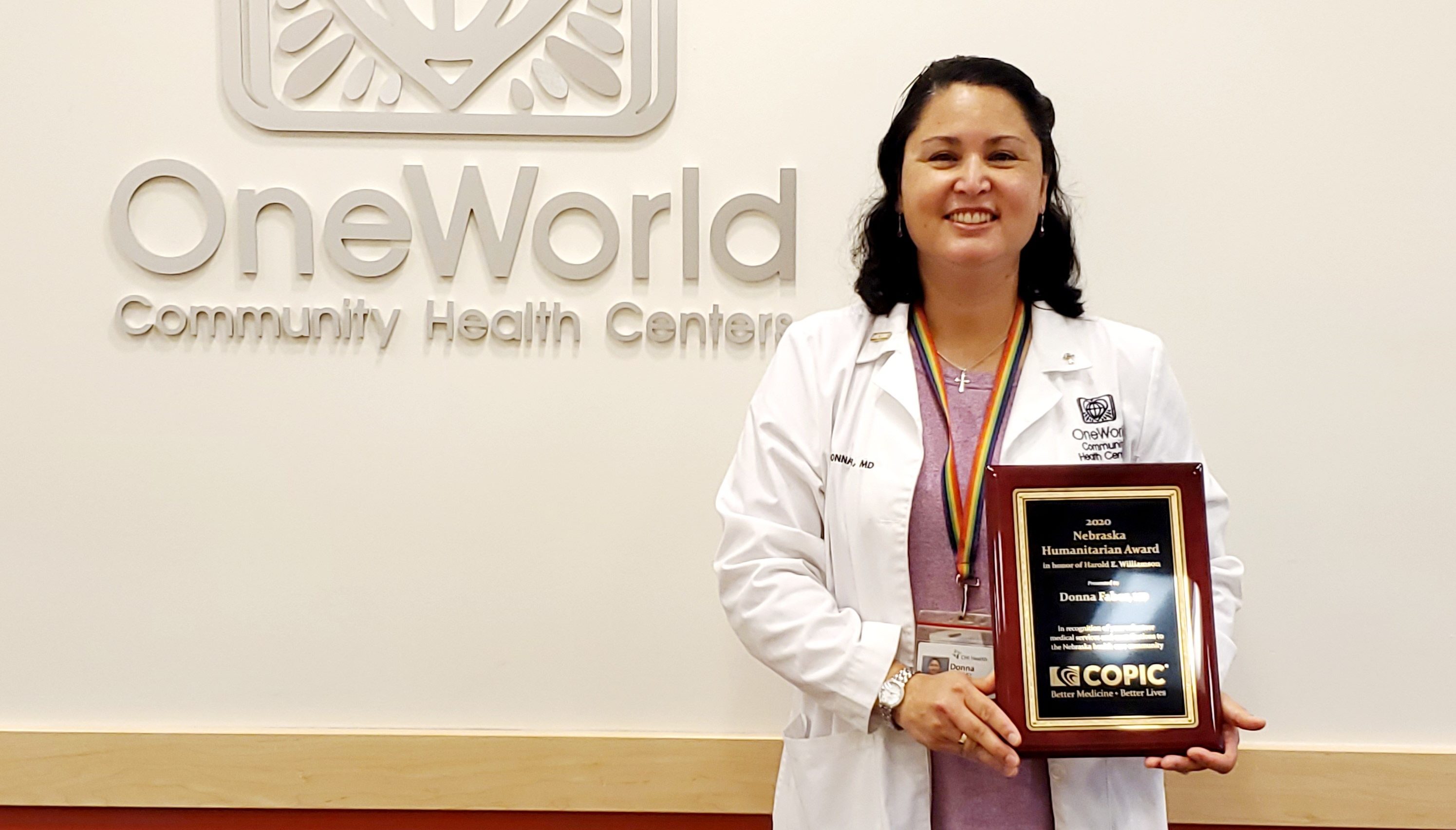 A person in a white coat holding a plaque