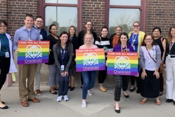 Members of OneWorld’s LGBTQIA+ Task Force holding signs.