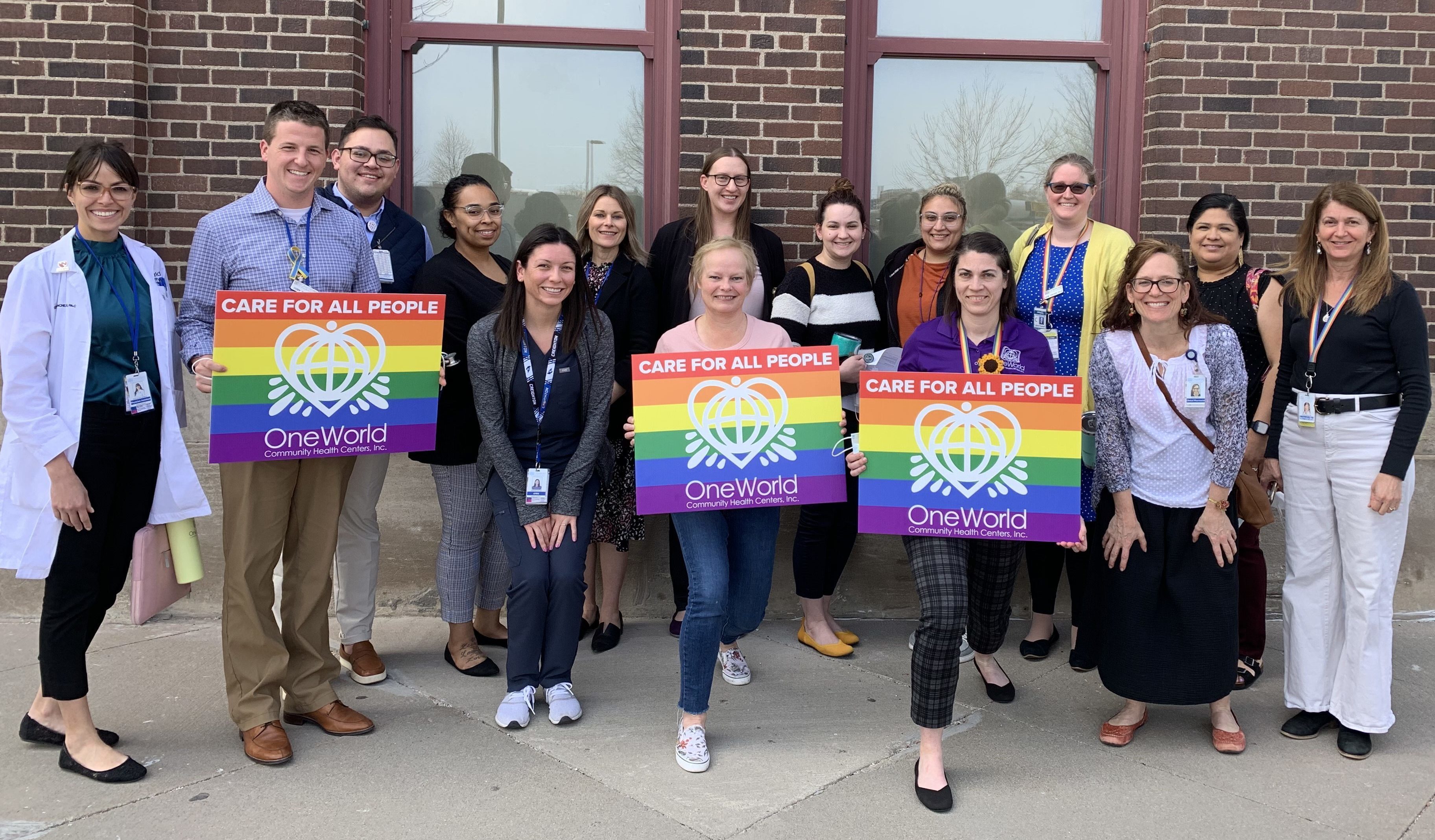 Members of OneWorld’s LGBTQIA+ Task Force holding signs. 