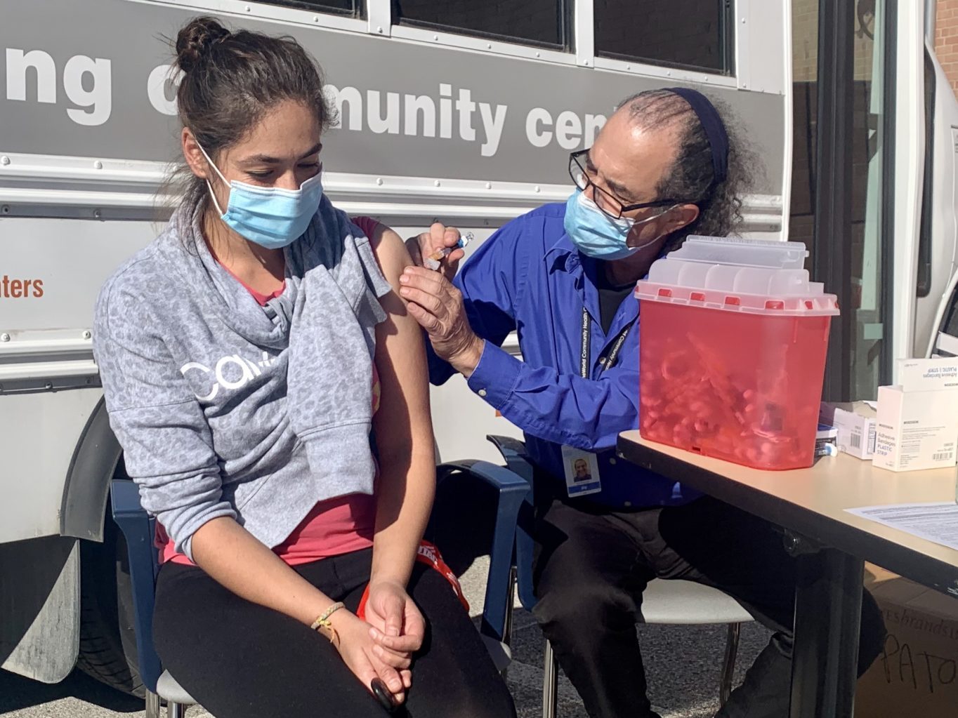 A OneWorld nurse giving a young woman a vaccine