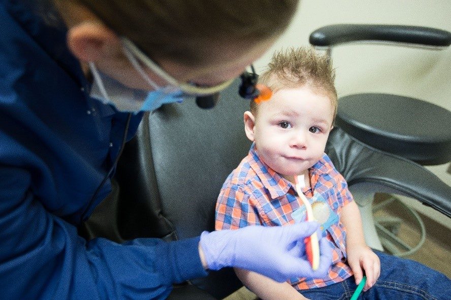 A dental hygienist holding a child's toothbrush