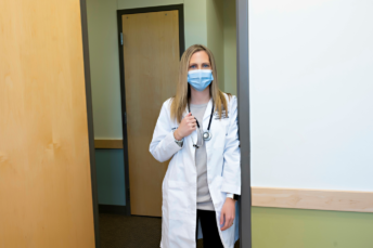 Laura Loewens, APRN standing in a hallway wearing a mask