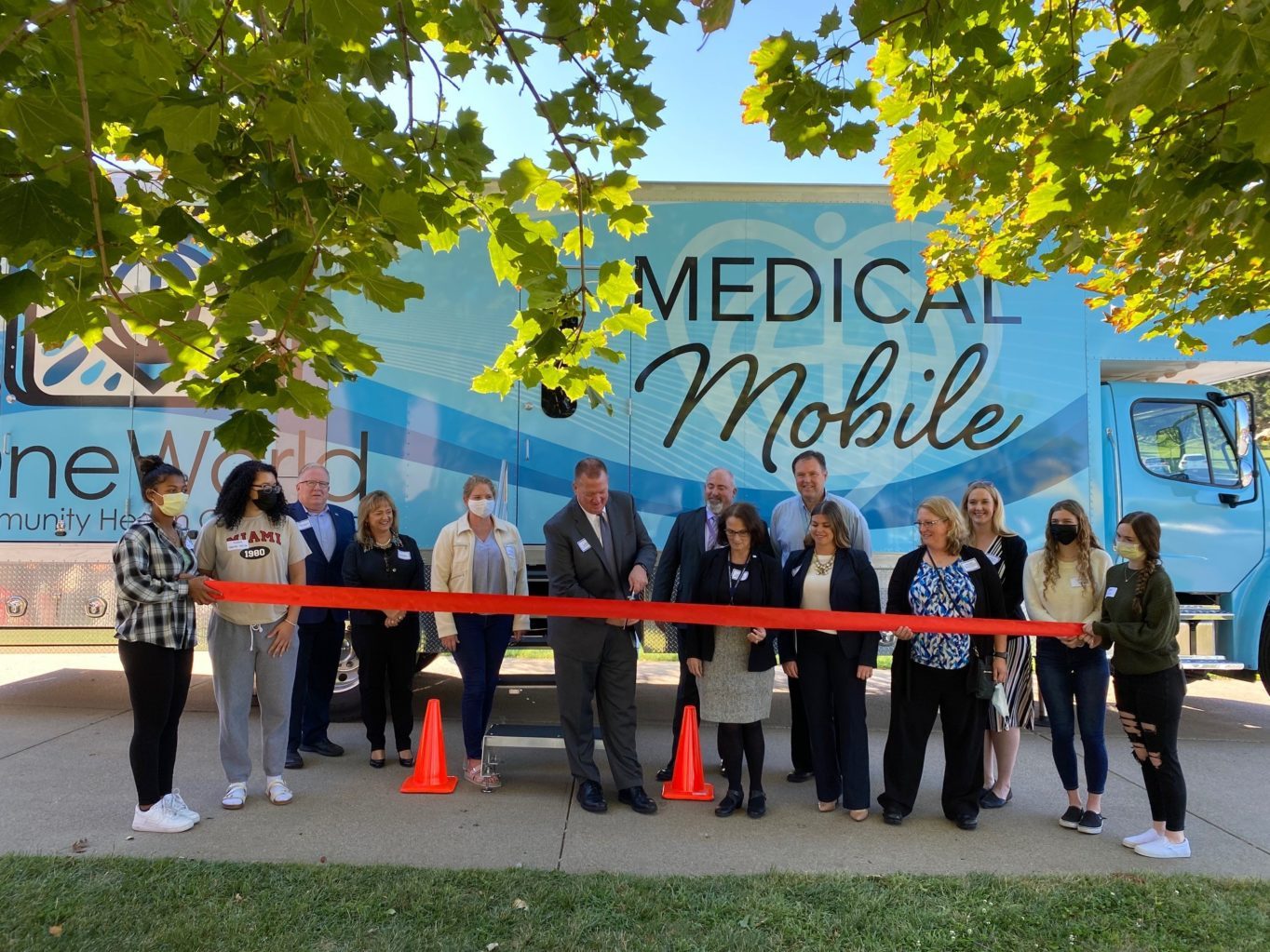 A group of people cutting a red ribbon