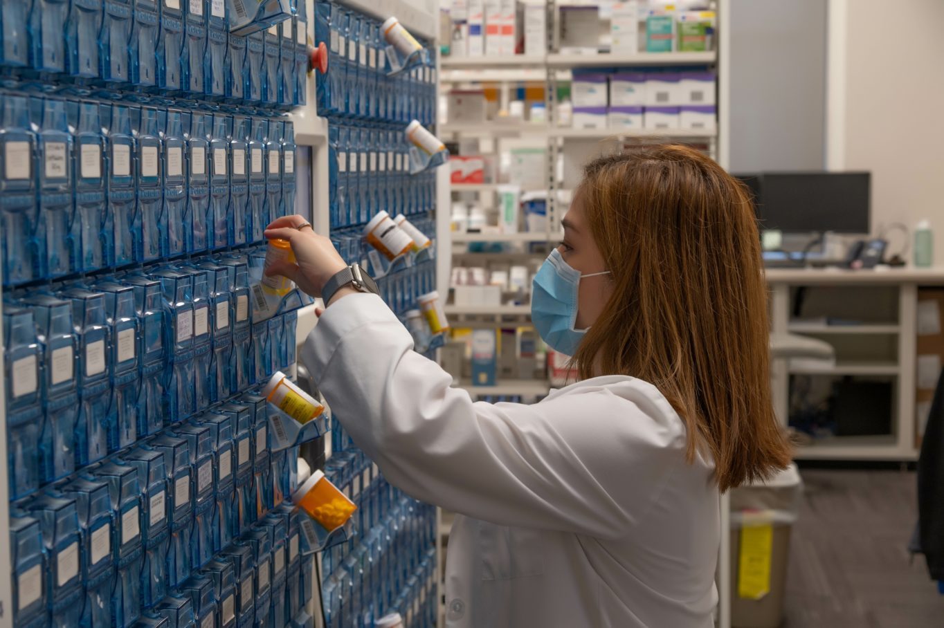 A person wearing a mask and holding a medicine bottle