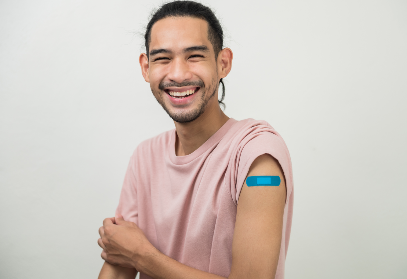 A young man smiling with a bandage on his arm