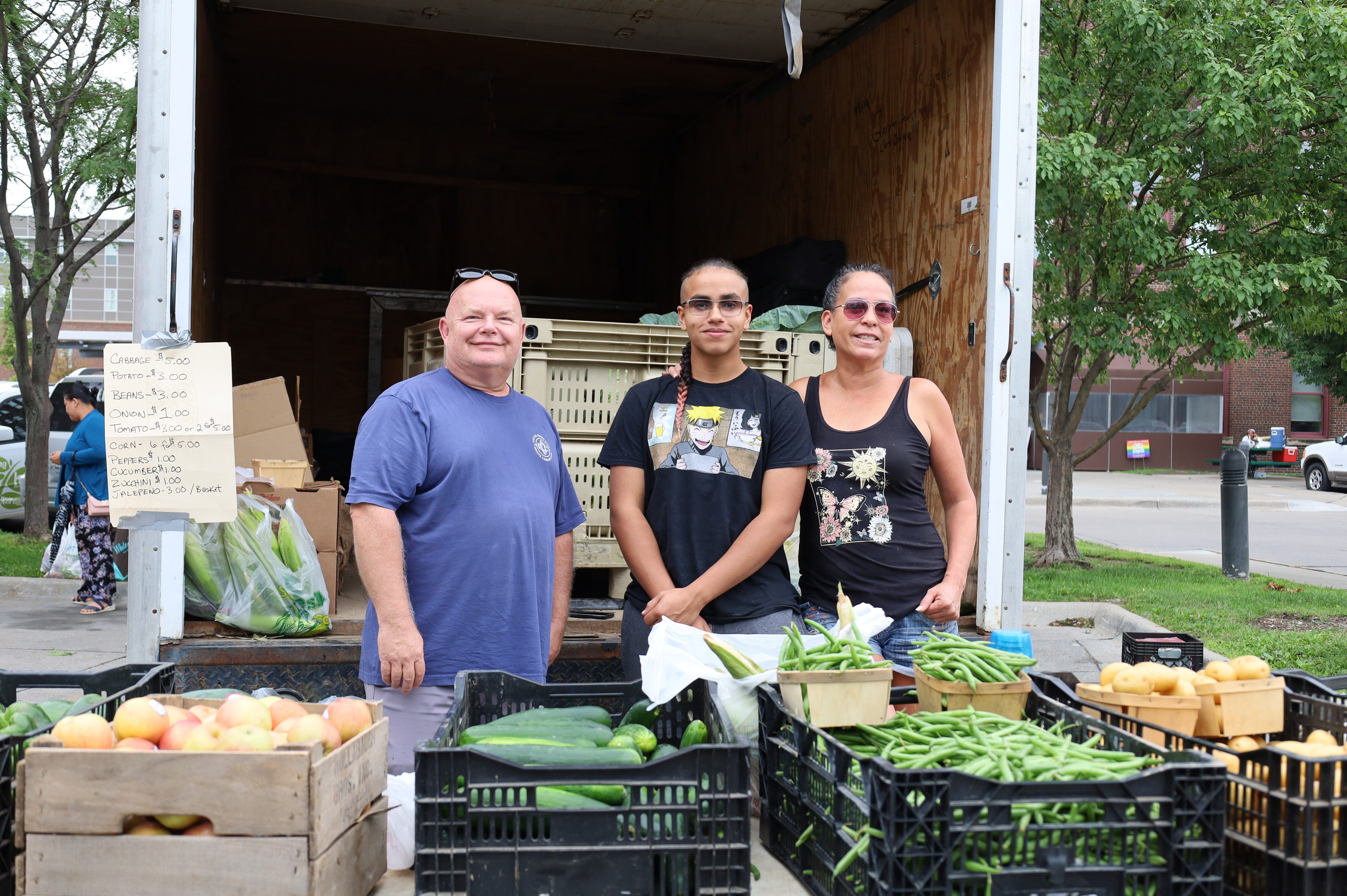 A group of people standing next to baskets of fruits and vegetables