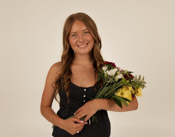 Martha Mullen smiles and holds a bouquet of flowers.