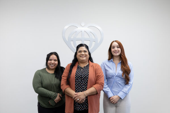 Three members of the OneWorld Customer Service Phones Medical team stand and smile.