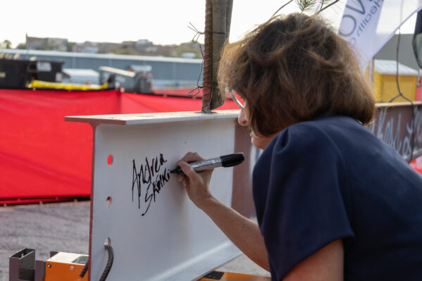 OneWorld CEO Andrea Skolkin signs the final beam before it is placed.