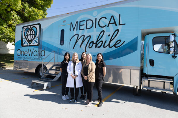 Five OneWorld employees stand in front of the Medical Mobile Clinic.