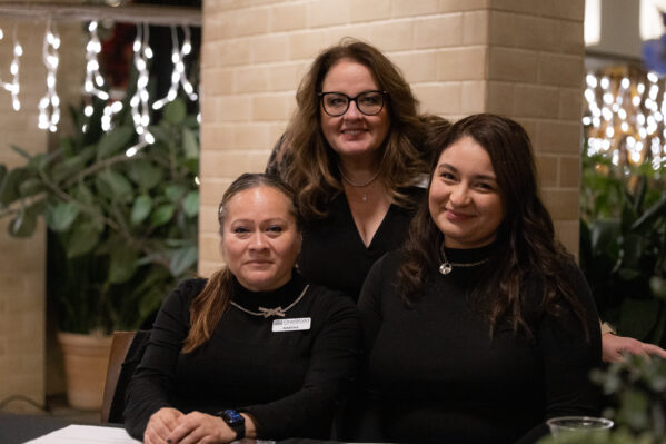 Three volunteers gather behind a registration table and smile. 